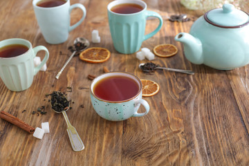 Cups and teapot with hot beverage on wooden table