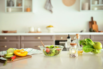 Bowl with salad and ingredients on kitchen table