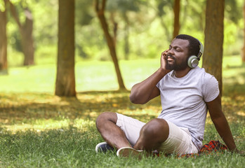Naklejka na ściany i meble African-American man listening to music in park