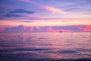 Deeply purple suset.Nature in twilight period which including of sunrise over the sea and the nice beach. Summer beach with blue water and purple sky at the sunset.