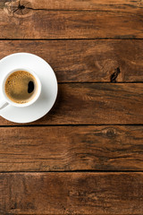 Black coffee cup on retro wooden background with copyspace. Top view