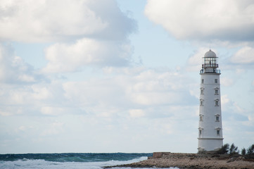 overcast weather concept white lighthouse on edge of the world near stormy sea with waves on cloudy sky backdrop with copy space