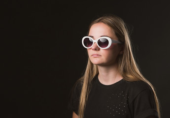 Naklejka premium A pretty brown-haired woman in a black t-shirt and dark glasses in a white frame