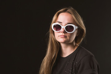 A pretty brown-haired woman in a black t-shirt and dark glasses in a white frame