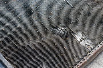 The surface of the car cooling radiator with marks of impacts by stones on a road