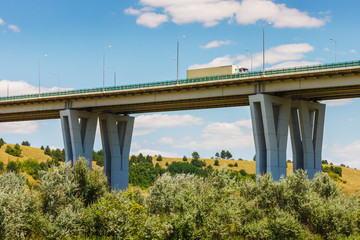 The modern bridge above a green forest and a truck on it with blue sky background. Highway M4 "Don", Rossosh river, Rostov-on-Don region, Russia