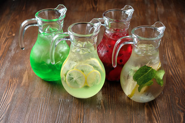 Different soft drinks in transparent jugs on a dark wooden background. menu for catering