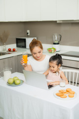 Happy Asian family are eating breakfast and see digital tablet in the kitchen at home. Healthy food and Morning activities