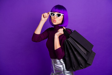 Beautiful stylish lady holding many packs in hands send air kiss dressed in trendy outfit isolated purple background