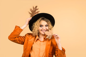 Beautiful young happy girl with autumn leaf. Autumn sale. Fashion woman with leaves. Fashion trends for fall. Autumn woman in black hat. Autumnal foliage. Autumn Clothing and color trends. Leaf fall.