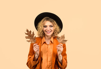 Autumn mood. Autumn fashion model. Fashion trend for fall. Smiling girl with yellow leaf. Woman with yellow leaves. Woman with autumn leaves. Autumn time. Season sale. Discount. Sale. Leaf fall.