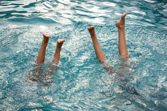 Two peoples legs in swimming pool water