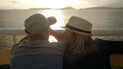 A man and woman in love looking at sunset from the deck of a cruise ship sailing the Mediterranean sea. Greece. 4K