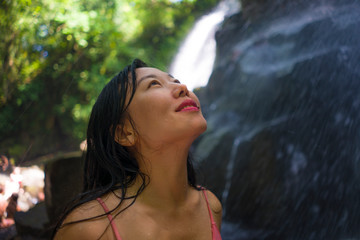 outdoors Summer holidays lifestyle portrait of young happy and beautiful Asian Chinese woman in bikini enjoying at tropical paradise waterfall feeling free and relaxed