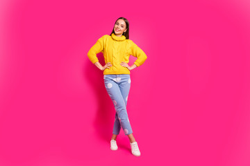 Fototapeta na wymiar Full body of attractive lady with her hands on waist wearing knitted sweater dotted denim jeans isolated over fuchsia background