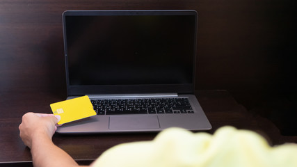 Girl hand with laptop computer and credit card for paying.Woman making transaction and shopping online with debit card and the keyboard in internet.