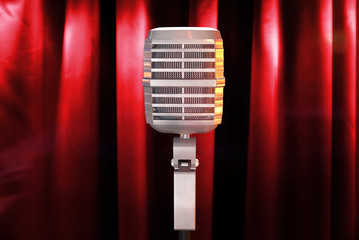Retro microphone with background red curtain on the stage.