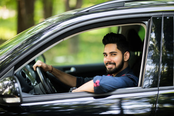 A handsome indian man drive his car on the road