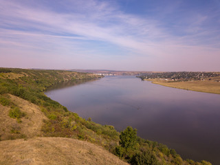 Top view of Dnestr (Dniester) river in autumn. River surrounds yellow field and green forest. Moldova republic of.