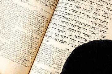 An open old Jewish book. Black jewish bale lies on an open scripture page. Selective focus. Closeup...