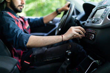 Transportation and vehicle concept - Indian man using car audio stereo system