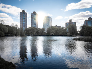 A shot of Central Park during a beautiful sunny day, with buidlings reflecting into the water of a lake. New York City, United States