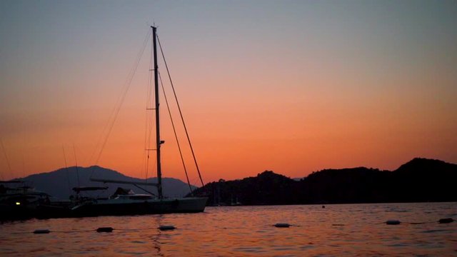 This shot depicts an evening view by the seaside in Turkey, Marmaris with a backdrop to some boats and mountains.