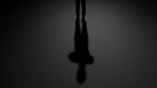Silhouette of a man and him shadow on a concrete floor. A dark background. Mystery animation.