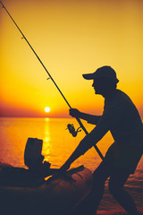 Silhouette of a fisherman fishing in sunset time on the open sea.