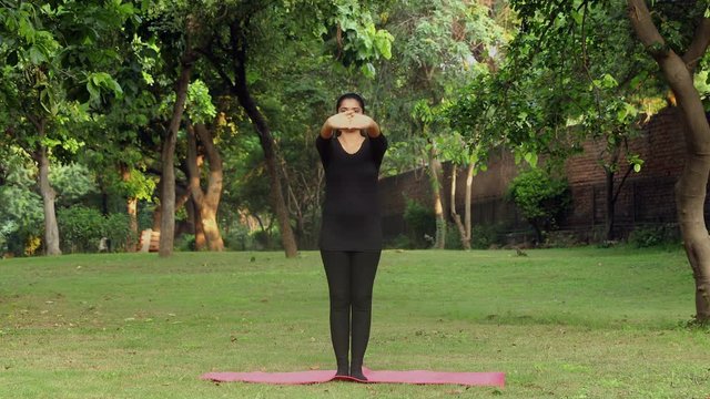 A young girl practicing tadasana / mountain yoga pose outside in a park. 