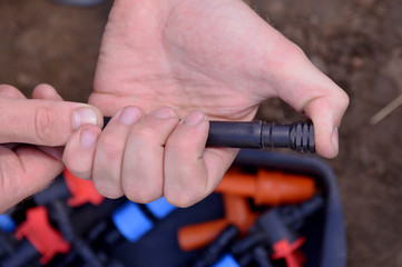 Prepared for planting in early Spring. faucet with red handle for drip irrigation. Drip Irrigation System Close Up. hose for drip irrigation in a skein. DIY drip irrigation system assembly