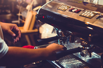 Closeup of professional male barista hand making cup of coffee with coffee maker machine in restaurant or coffee shop. People and lifestyles. Business food and drink concept. Shop owner theme