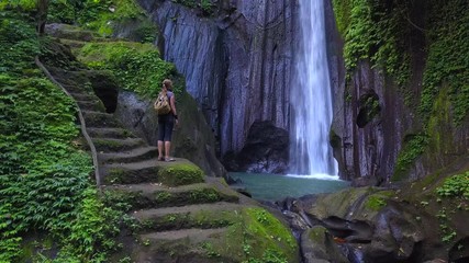 Woman walks through and  enjoying view at the waterfall in Bali island, Indonesia