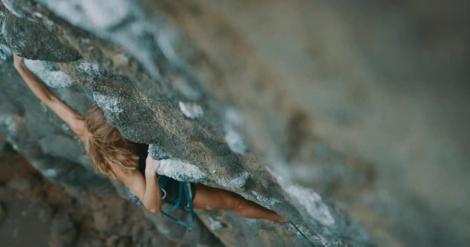 Strong fit woman rock climbing on tough sport route, rock climber makes a big move and falls