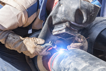Construction worker welding pipes on a heavy site.