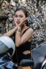 Obraz na płótnie Canvas Asian girl in a black dress on a scooter. Beautiful Balinese women lifestyle portrait