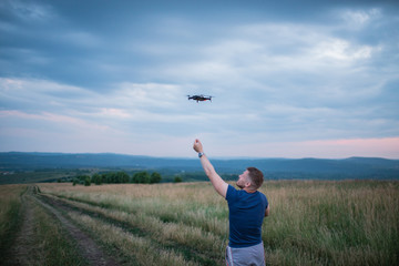 Fototapeta premium The young man manipulates the drone using the control panel. New technologies and trends in photo and video recording. record footage in the air.