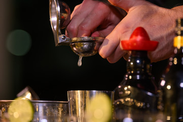 Closeup bartender hand preparing fresh juice cocktail in drinking wine glass with ice at night bar clubbing counter. Occupation and people lifestyles concept. Outdoor and nightclub background