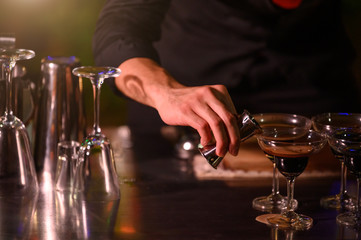 Closeup bartender hand preparing fresh juice cocktail in drinking wine glass with ice at night bar clubbing counter. Occupation and people lifestyles concept. Outdoor and nightclub background