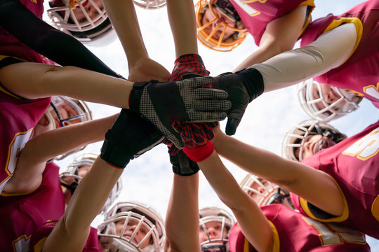 Photo of female rugby players stacking their hands together