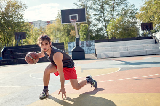 Image of athlete in blue T-shirt playing basketball on playground