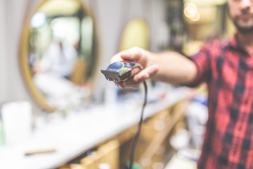 Close up of fashionable hipster hairdresser holding hair trimmer.