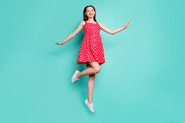 Full size photo of lovely girl smiling jumping wearing polka dot skirt dress isolated over teal turquoise background