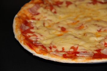 Fresh appetizing pizza with delicious ingredients isolated on black background