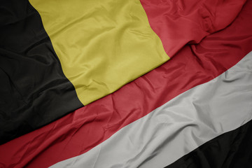 waving colorful flag of yemen and national flag of belgium.
