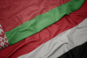 waving colorful flag of yemen and national flag of belarus.