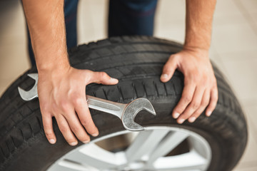 mechanic holding tyre and car spanner close up