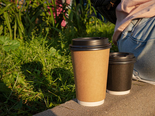 Two disposable cups on the curb next to the girl