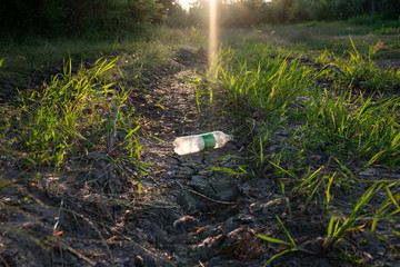 White empty plastic bottle lying on the cracked dry ground