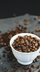 Coffee bean on a white cup over a marble, rock stone slate dark background. 